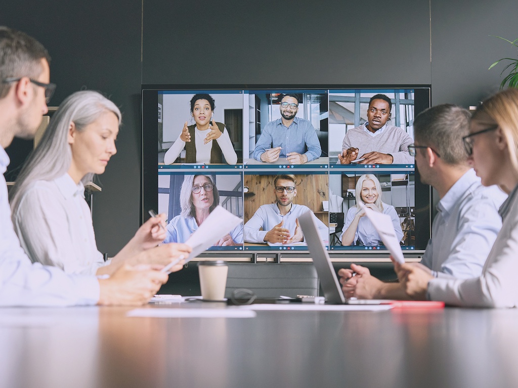 A business meeting with hybrid team members on screen, symbolizing ZeroTier's secure connectivity for remote work and collaboration.
